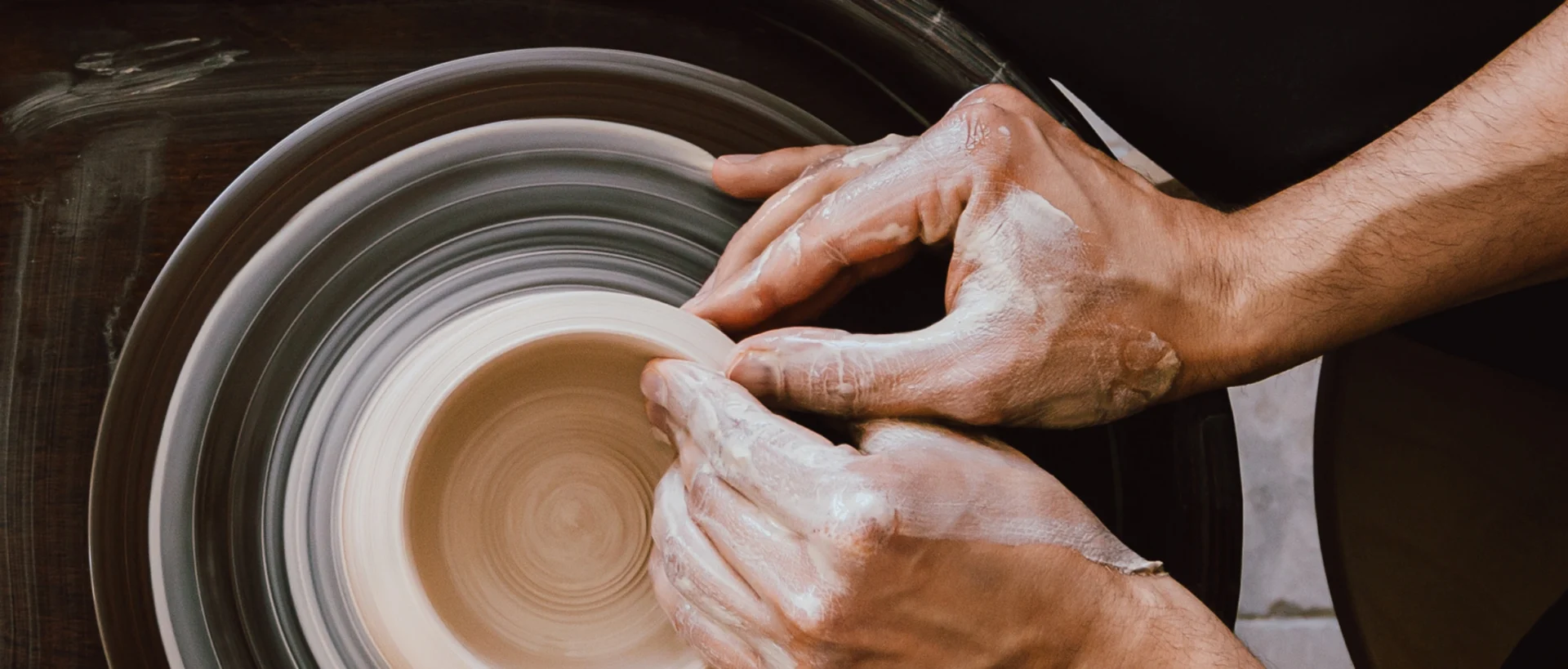 Close-up of a potter shaping clay on a spinning pottery wheel with hands.