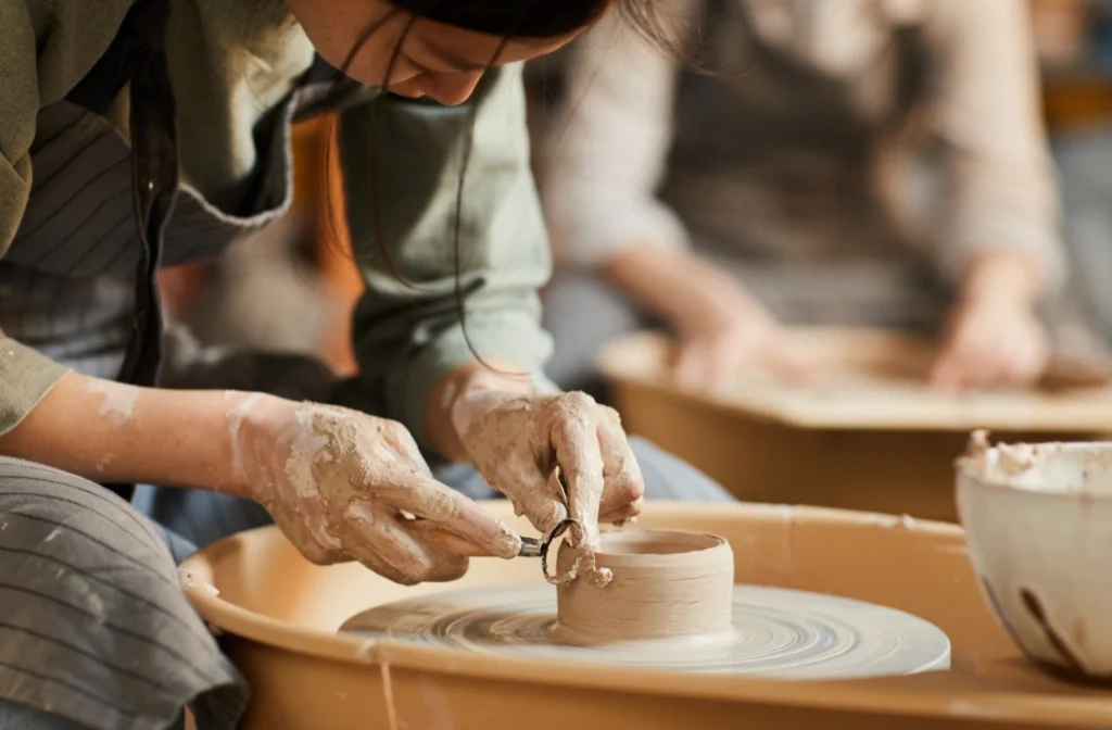 Person shaping clay on a pottery wheel, focusing on detailed handcrafting of a ceramic piece.