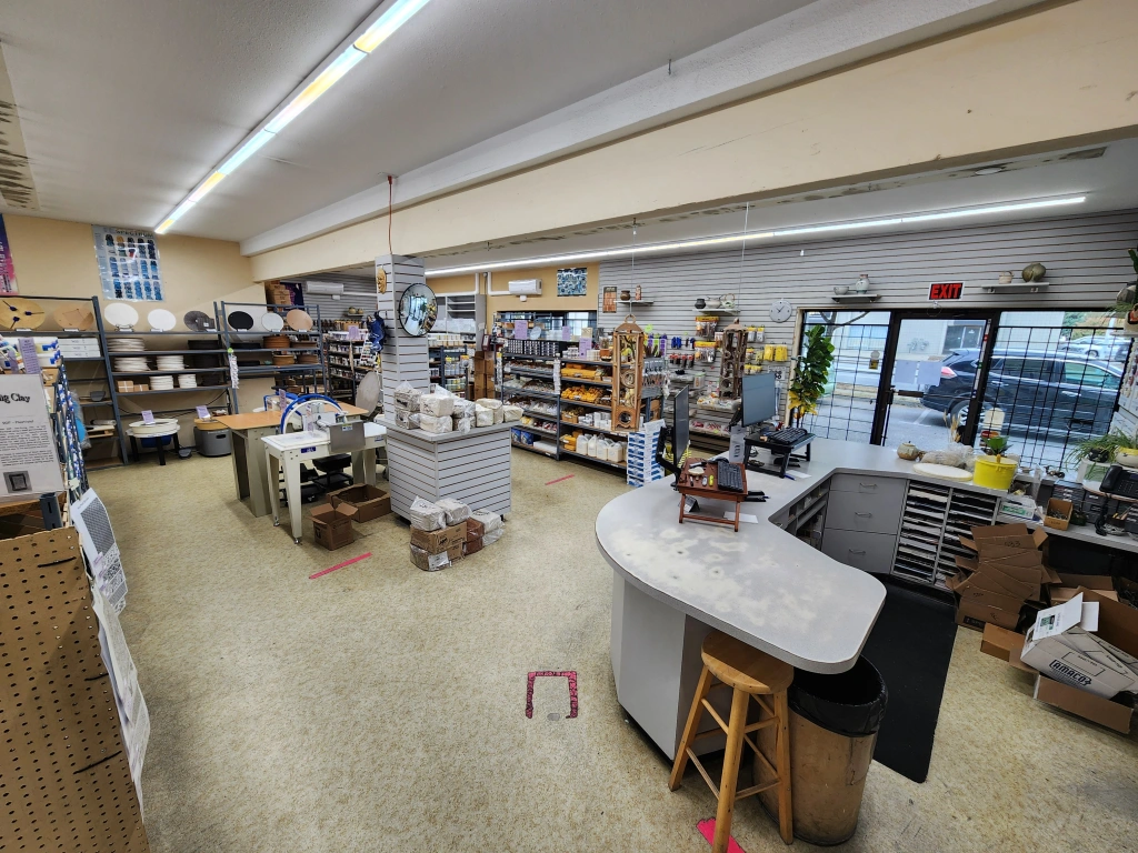 Interior view of a well-organized hardware store featuring stocked shelves, a service counter with stools, and various tools and supplies.