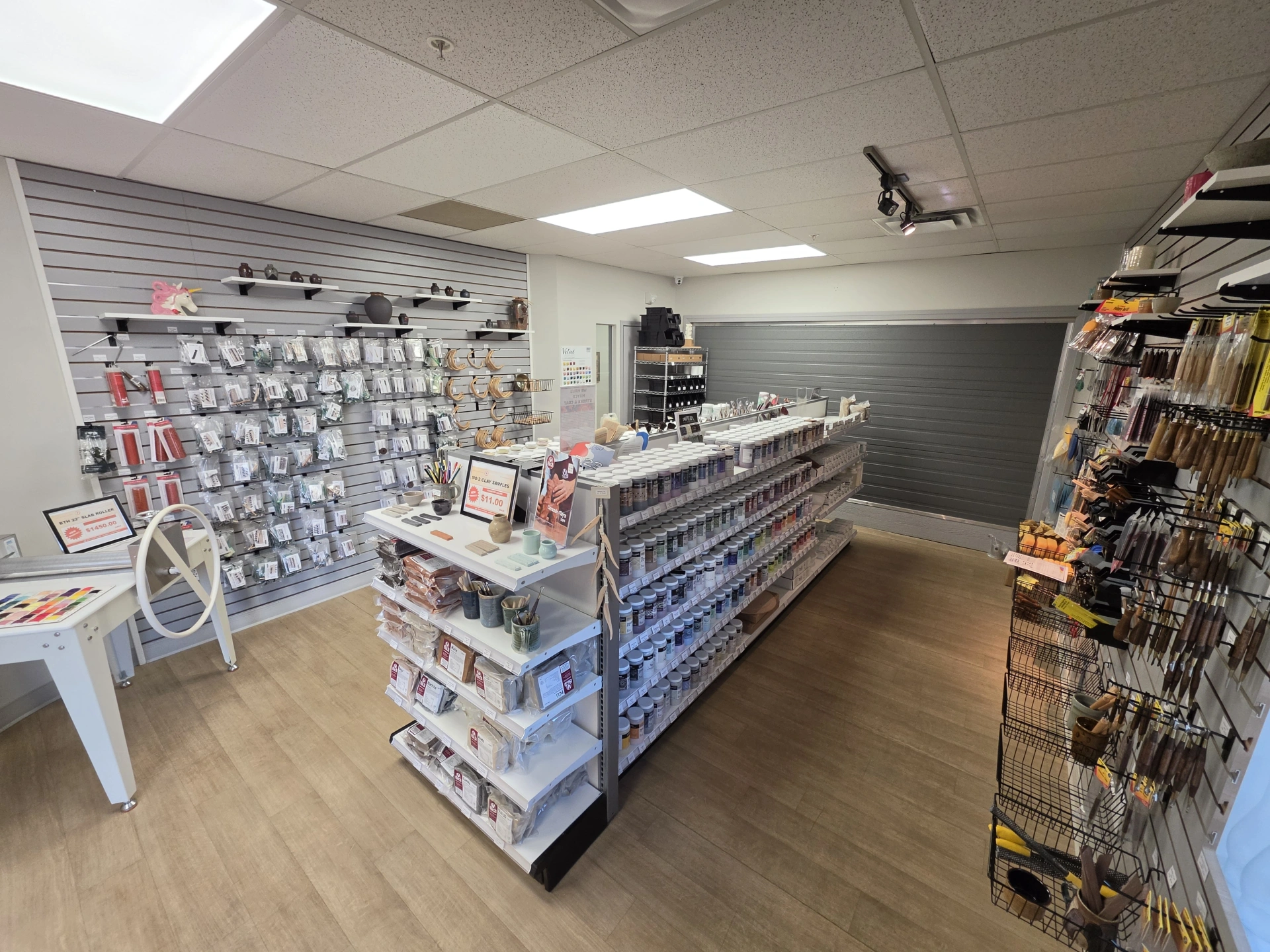Interior view of a well-organized retail store displaying various craft supplies and accessories on shelves and wall racks under bright ceiling lights.