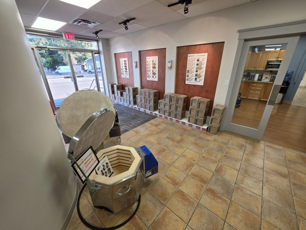Front interior view of a pottery studio featuring a kiln, clay stools, framed artwork on the walls, and a tiled floor.