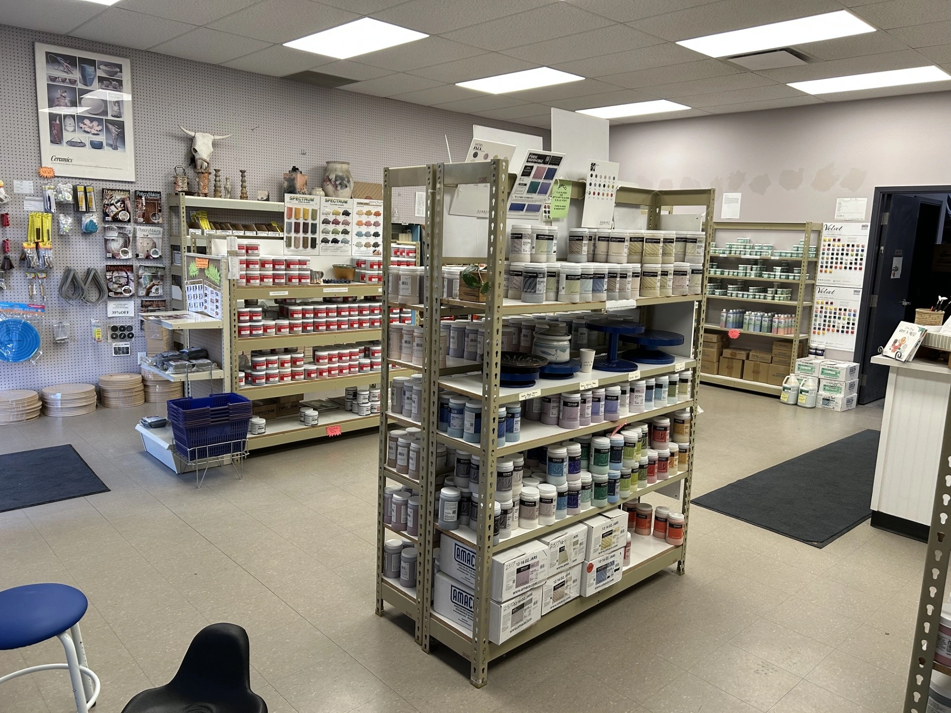 Shelves stocked with various art supplies and paint cans neatly organized in a well-lit craft store interior.