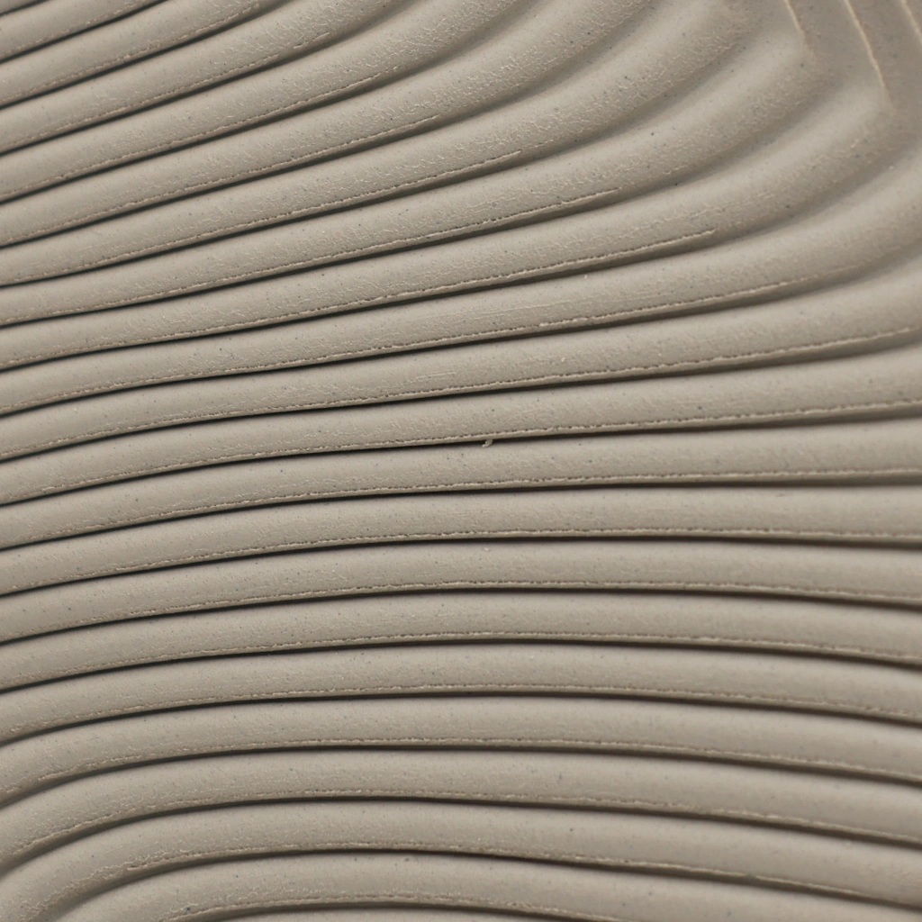 Close-up of smooth, curved, beige ridges creating a flowing, wave-like pattern on a textured surface.