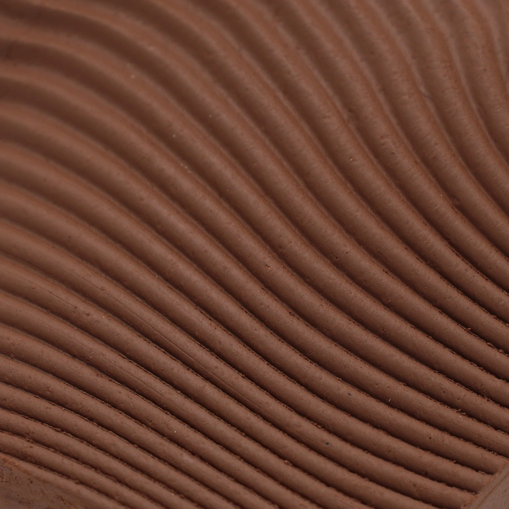 Close-up of textured brown fabric with evenly spaced, curved ribbed patterns creating a wave-like effect.