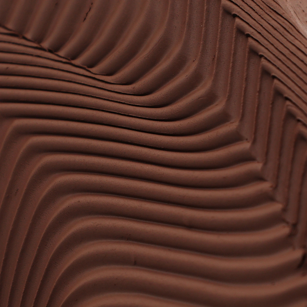 Close-up of textured brown fabric with wavy, folded patterns creating a 3D effect.