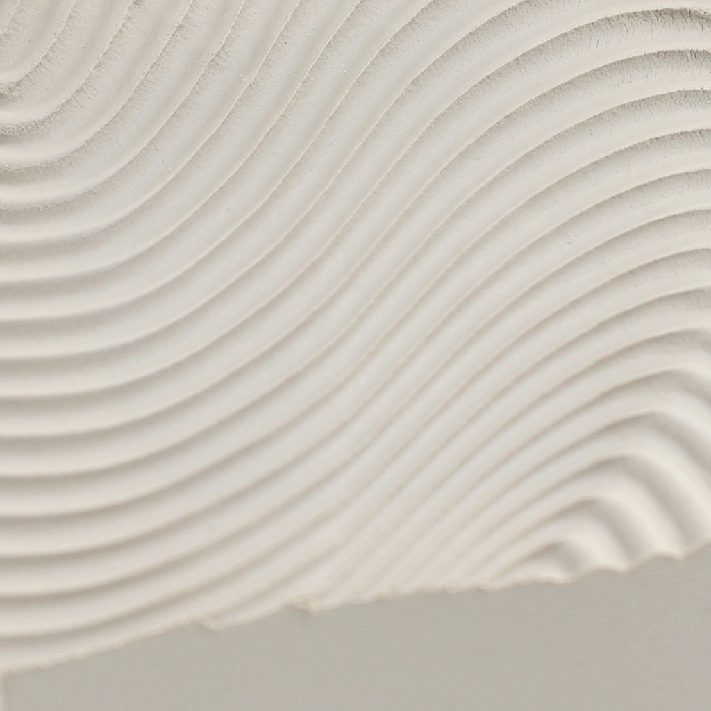 Close-up of a white textured surface featuring smooth, evenly spaced wavy ridges creating a flowing pattern.