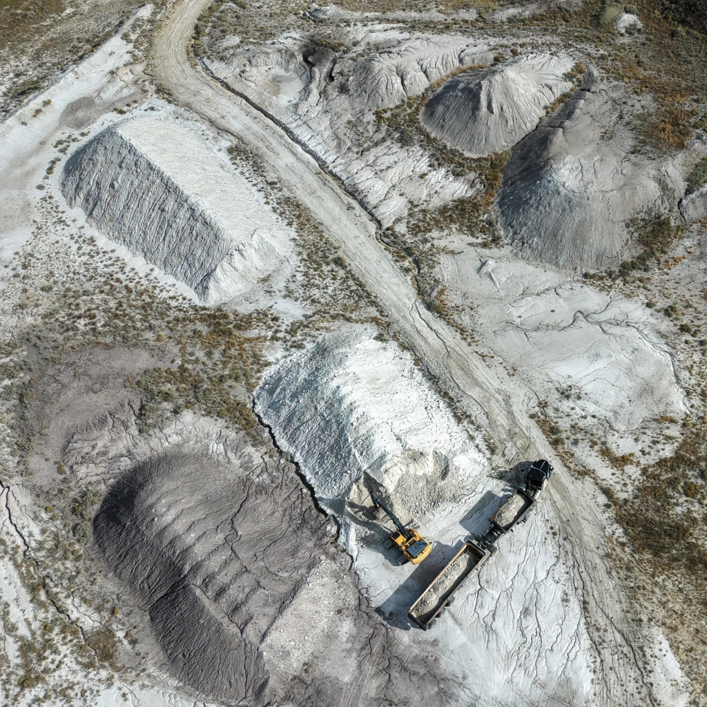 Aerial view of an excavator working piles of raw clay at a prairie clay deposit