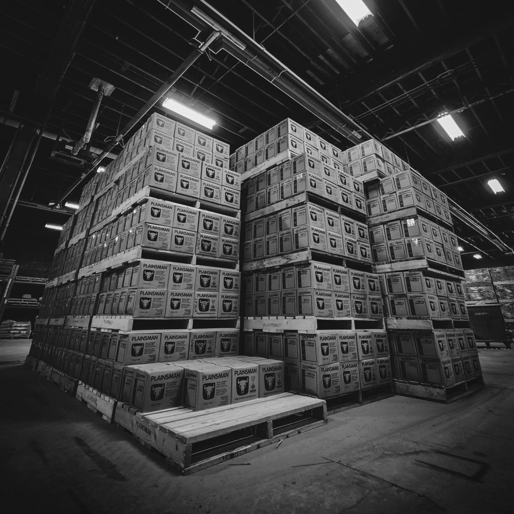 Black and white photo of boxed Plainsman clay stacked on pallets in the warehouse