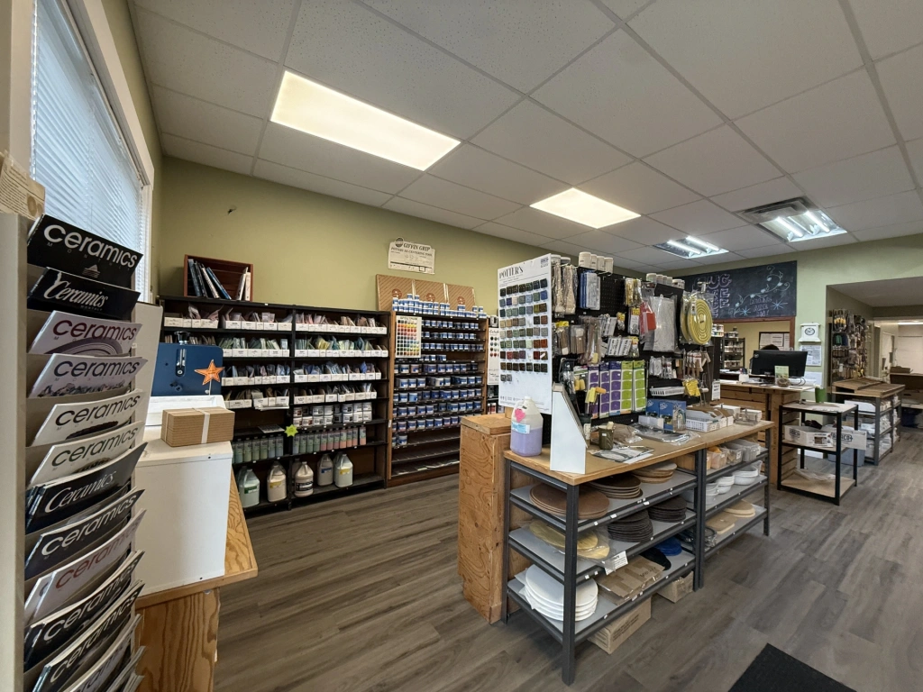 Interior view of a well-organized art supply store featuring shelves stocked with paints, brushes, and craft materials under bright ceiling lights.