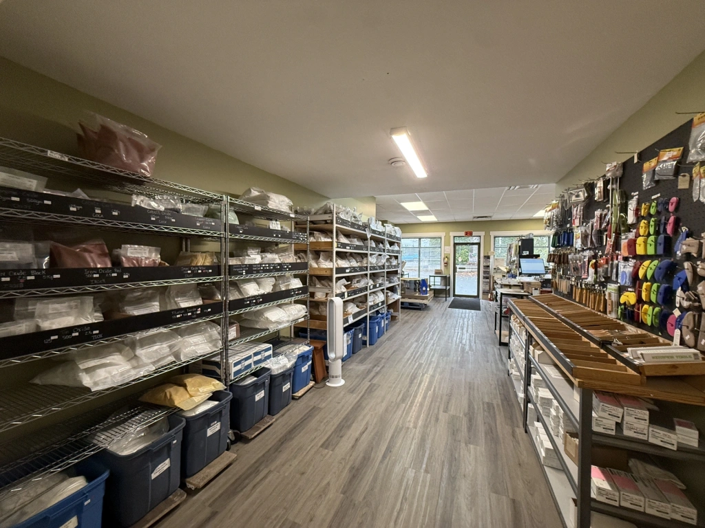 Interior view of a well-organized storage room with shelves holding various folded textiles, containers, and craft supplies.
